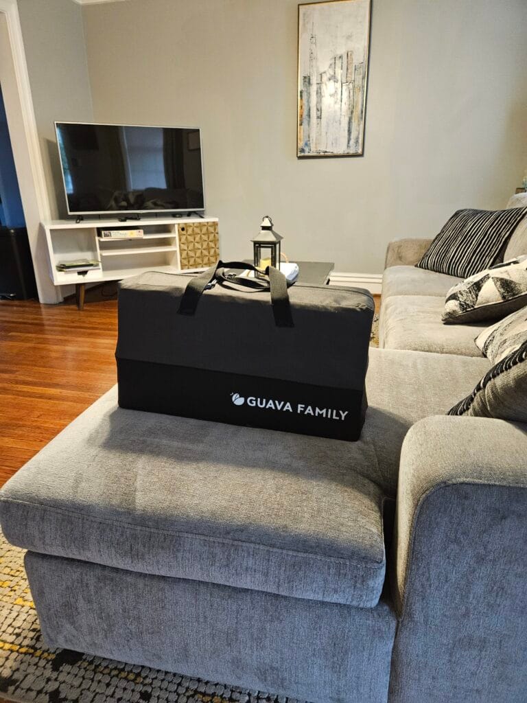 Guava Lotus Travel Crib Sitting on a couch
