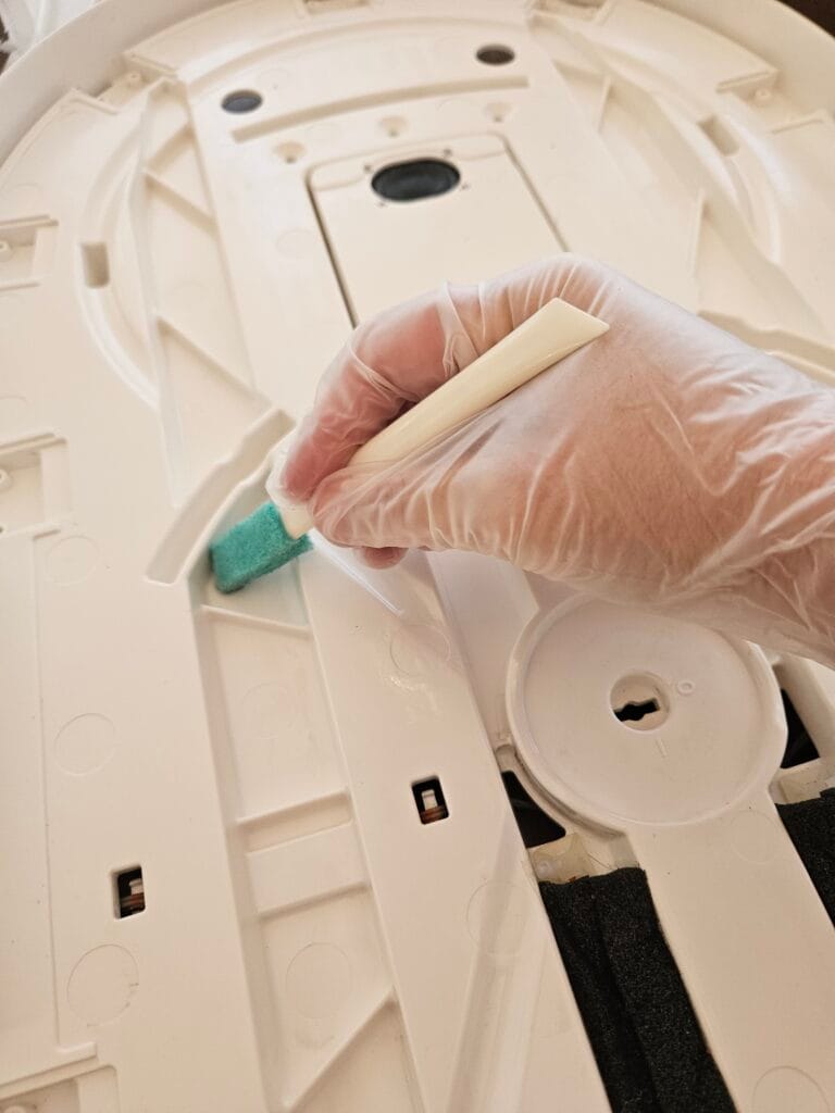 Close up of a hand with gloves cleaning a Snoo with gloves on.