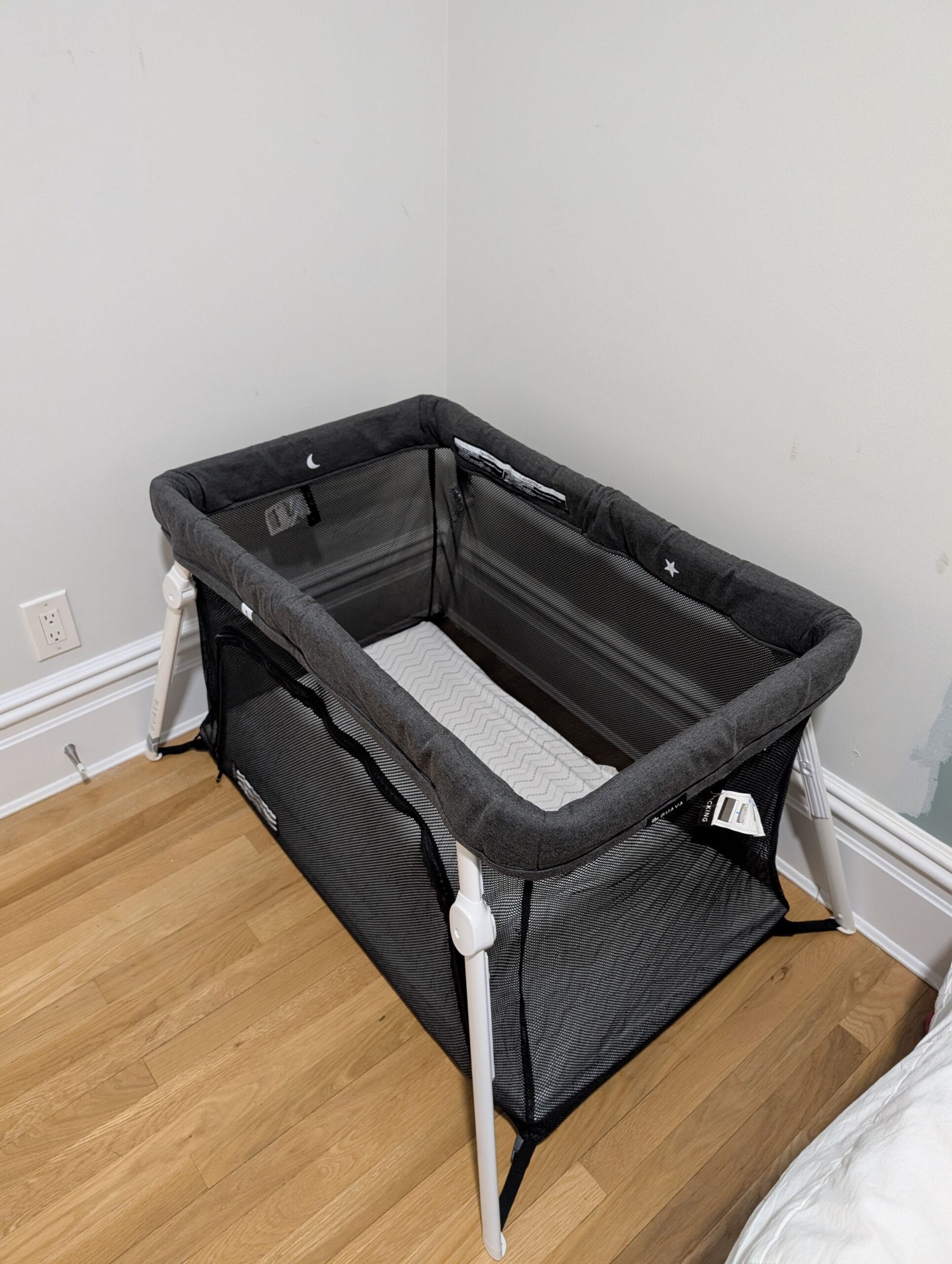 Guava Lotus travel crib set up in corner of a bedroom